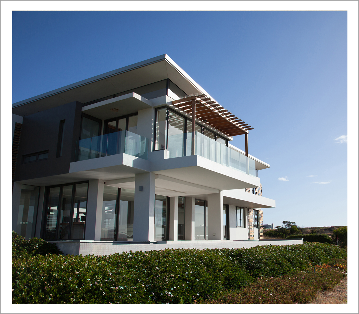 Modern two-story house with glass balcony.
