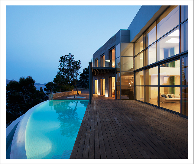 Modern glass house with wooden deck, infinity pool