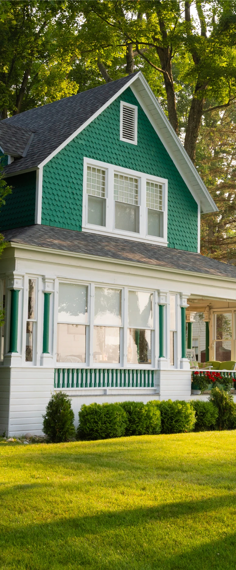 Green house with front porch and lawn.